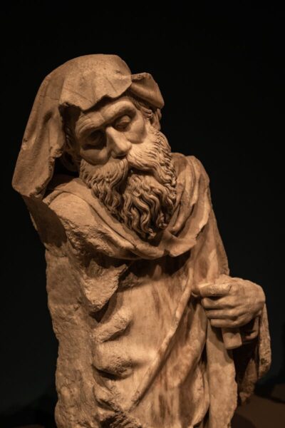Detailed close-up of an ancient bearded statue in Barcelona museum setting.