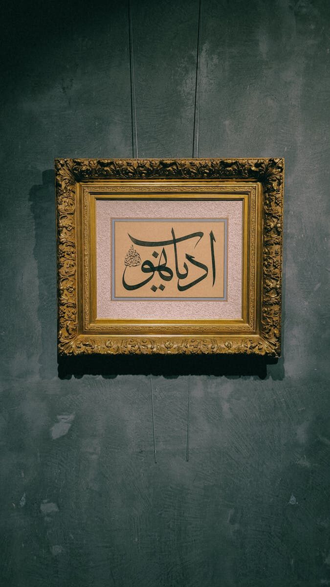 A beautiful framed piece of Arabic calligraphy displayed on a dark wall.