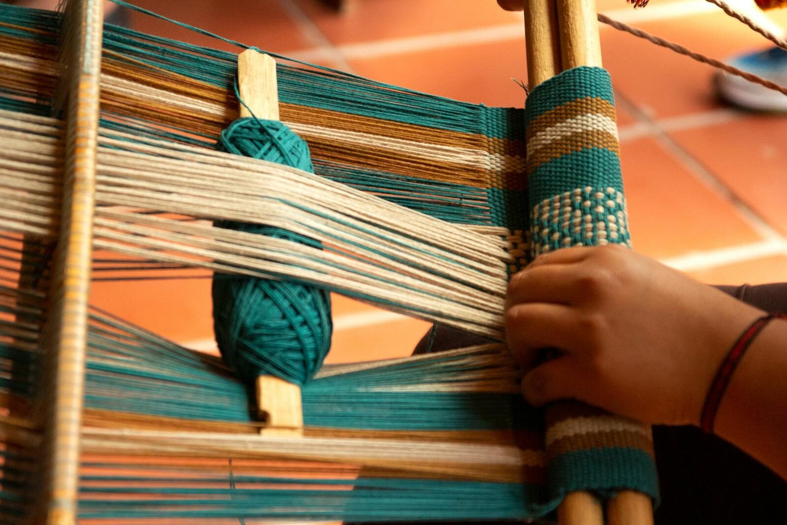Detailed view of a hand weaving tapestry with colorful threads on a loom.