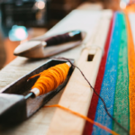 Bright threads on a loom captured in an artistic, colorful close-up.