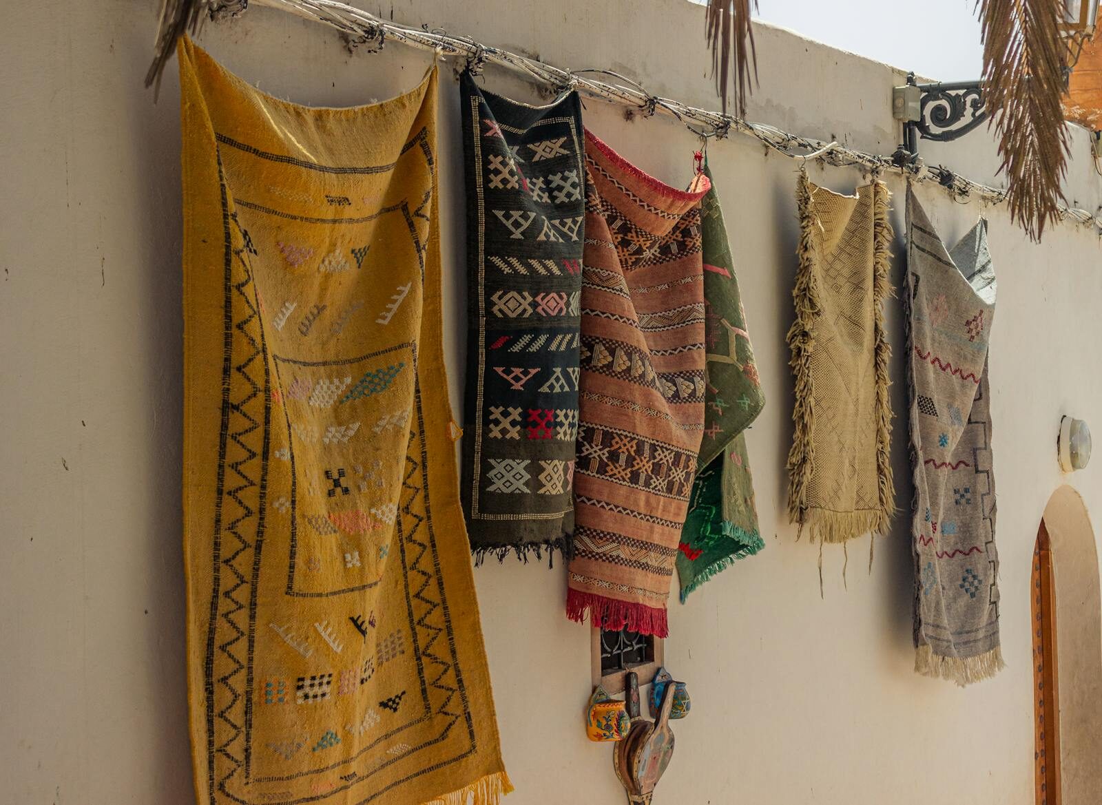 Colorful traditional rugs hung on a wall, showcasing intricate patterns.
