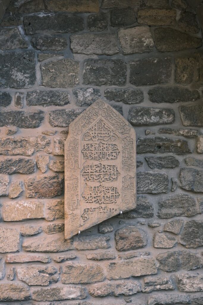 Intricate Arabic script on an old stone wall, showcasing historical craftsmanship.