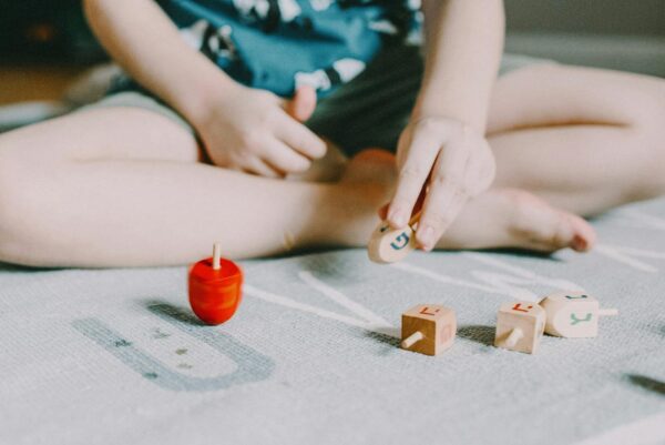 A young child playing with dreidels, a traditional Hanukkah toy, indoors.