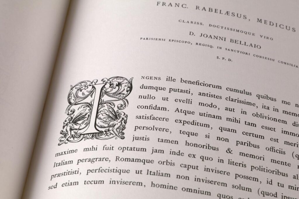 Close-up of an open book with intricate Latin text and decorative initials.