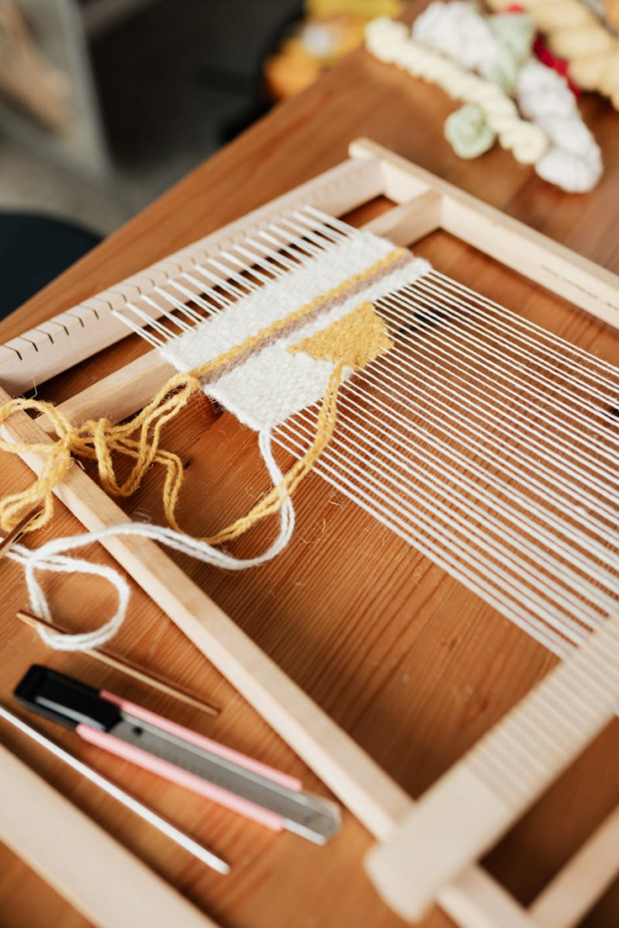 Close-up of a hand loom in a workshop, showcasing the weaving process with yarn.