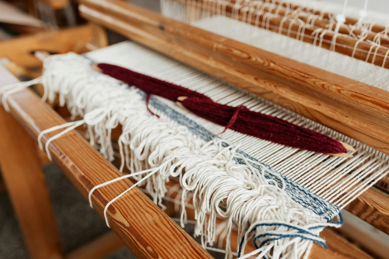 Close-up of yarn being woven on a wooden loom, showcasing traditional craftsmanship.