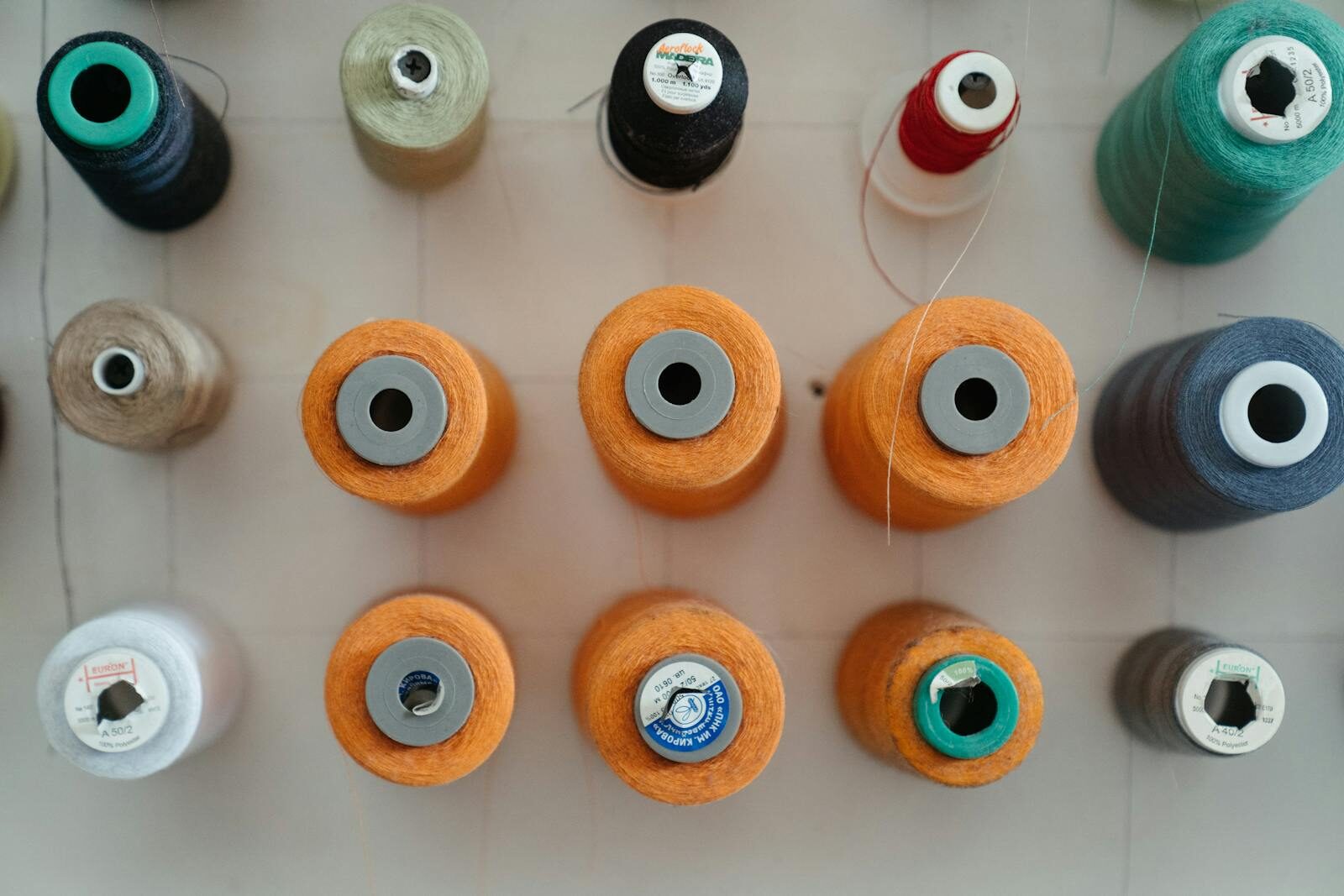 Top view of organized sewing thread spools in varying colors, perfect for crafting and tailoring.