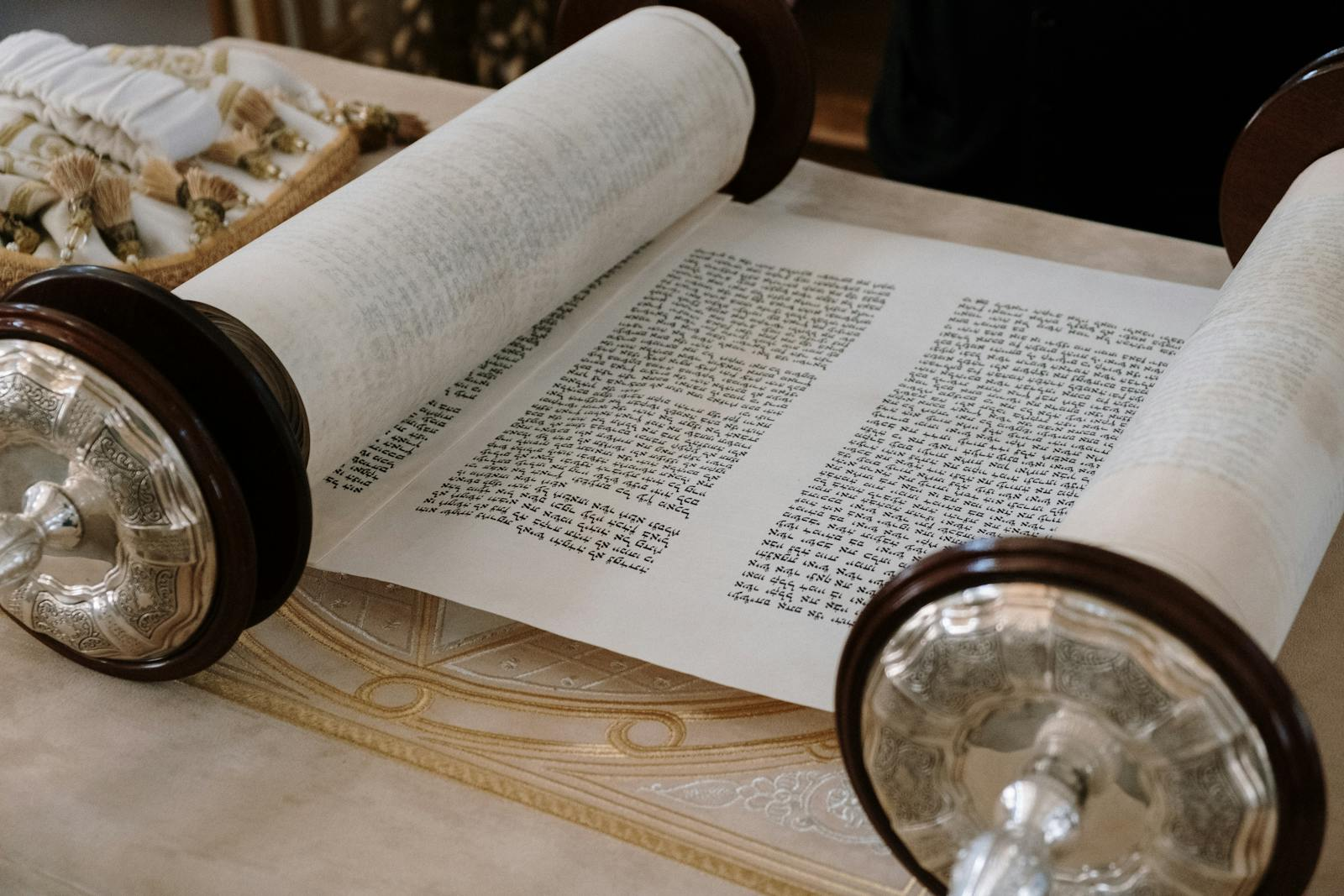 A close-up view of an open Sefer Torah on a synagogue table, highlighting intricate details.