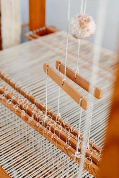 Detailed view of a wooden loom showcasing warp and weft threads, emphasizing the craft of weaving.