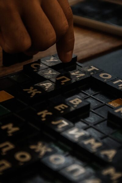Close-up of hands arranging Cyrillic letters in a board game, fostering creativity and fun.